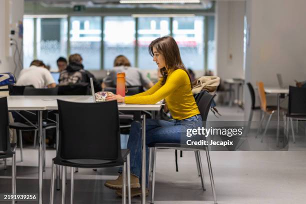 young female student using laptop at university - student sitting in desk side view stock pictures, royalty-free photos & images