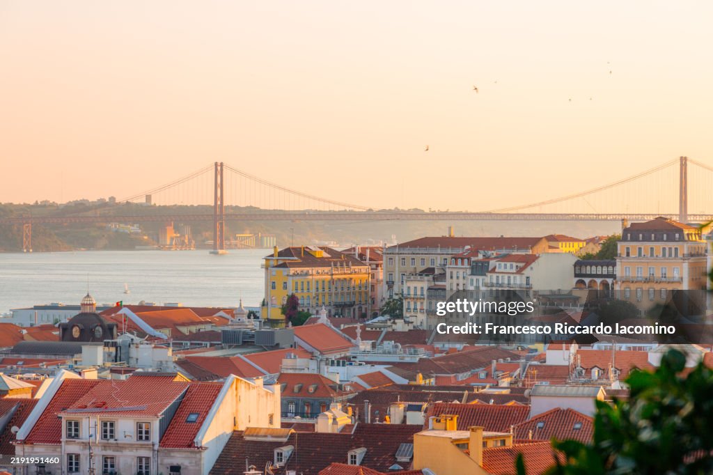 Lisbon, rooftops and bridge at sunset