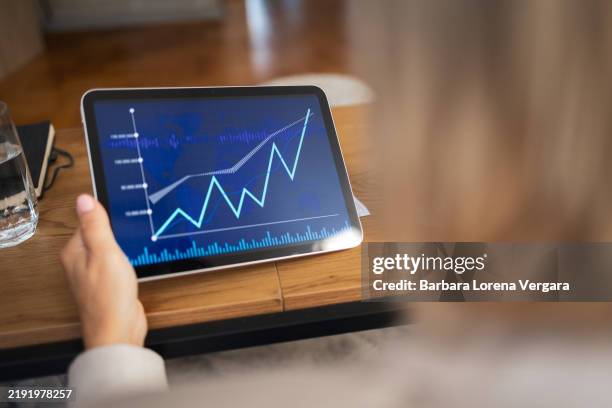 person analyzing financial graph on digital tablet in office setting - equipamento técnico médico imagens e fotografias de stock