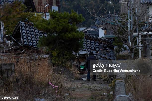 Woman walks past the debris of a collapsed house in a residential area on New Year’s Day on January 01, 2025 in Suzu, Japan. On January 1st a...