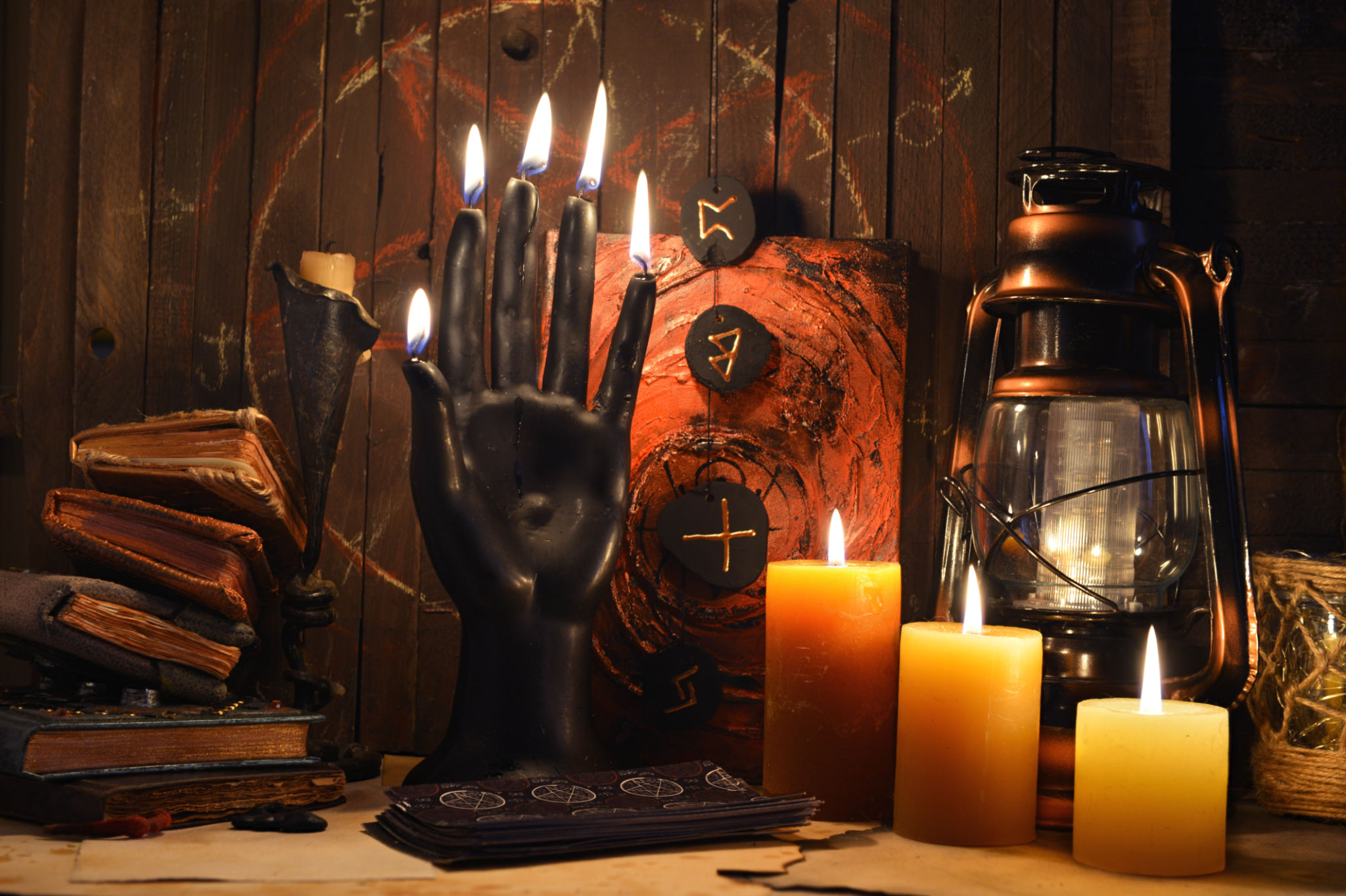 Mystic still life with black candle as scary hand, magic spell book, old lamp and witchy ritual objects on altar table. Occult, esoteric, wicca, Halloween and gothic concept. Mystic still life with black candle as scary hand, magic spell book, old lamp and witchy ritual objects on altar table. Occult, esoteric, wicca, Halloween and gothic concept.