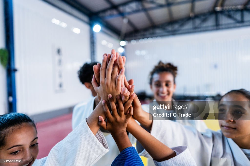 Judo athletes doing high-five on a dojo