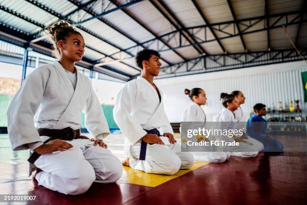 atleti di judo inginocchiati su un dojo - arte marziale foto e immagini stock