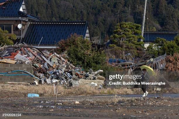 Woman walks past her neighbor's destroyed house site caused by Noto Peninsula earthquake on New Year’s Day on January 01, 2025 in Suzu, Japan. On...