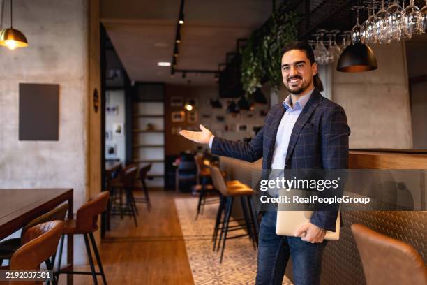 restaurant manager showing his establishment with a welcoming gesture - welcome sign stock pictures, royalty-free photos & images