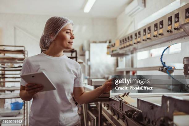 tech-savvy female baker using tablet for bakery operations - industri bildbanksfoton och bilder