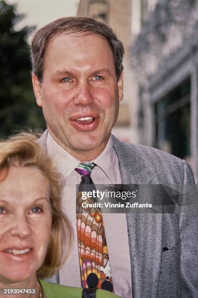 American media executive Michael Eisner, wearing a striped grey blazer over a pale pink shirt and a 'Mickey Mouse' tie, attends the Hollywood...