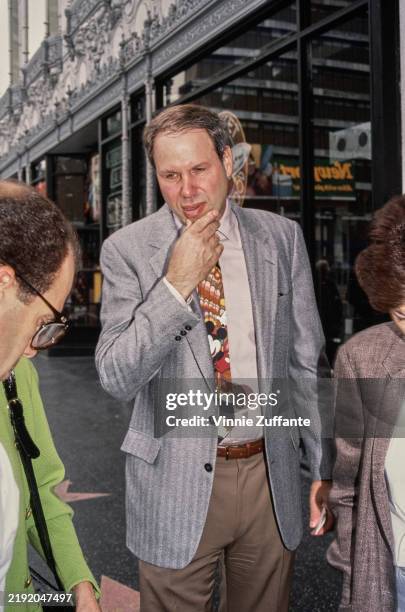 American media executive Michael Eisner, wearing a striped grey blazer over a pale pink shirt and a 'Mickey Mouse' tie, attends the Hollywood...