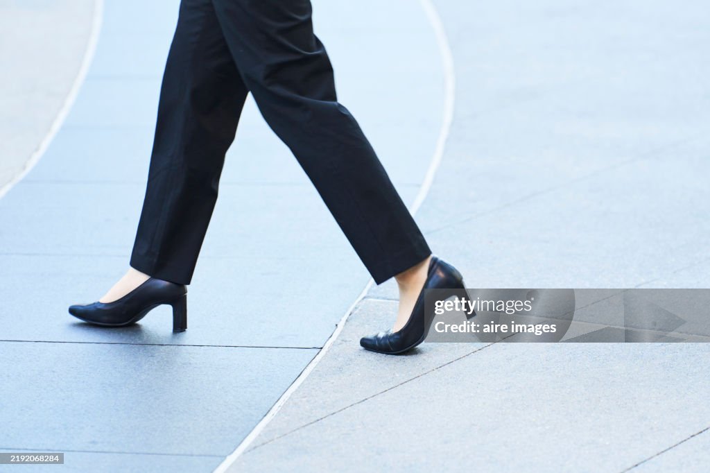 Businesswoman walking on city street in high heels