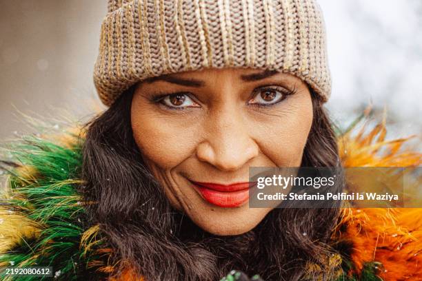 beautiful woman wearing a knitted cap and feathered scarf - abrigo de colores fotografías e imágenes de stock