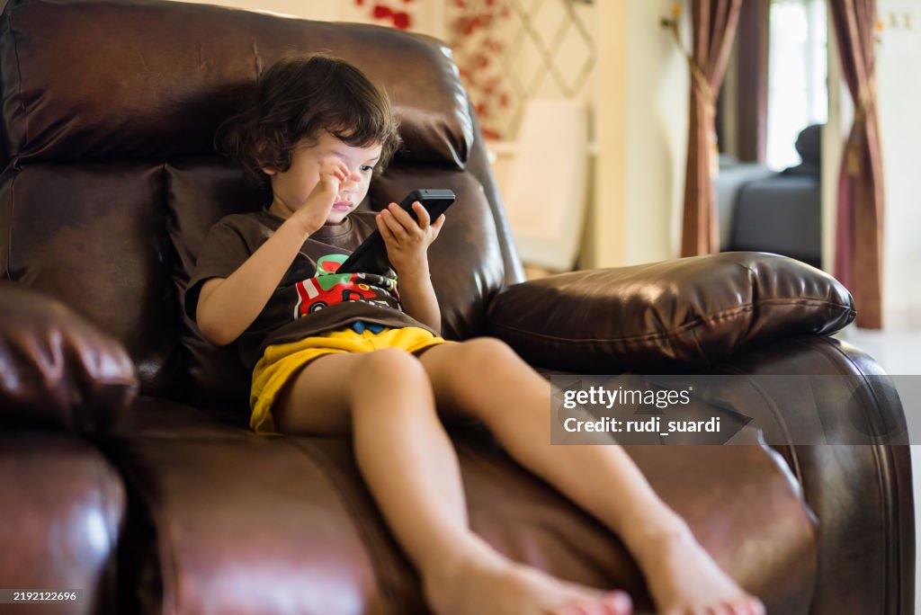 Boy playing alone on smart phone in living room