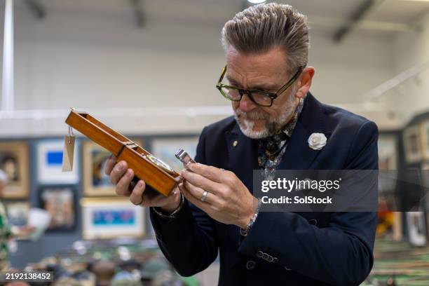 auktionator bei der inspektion einer uhr - versteinerung stock-fotos und bilder