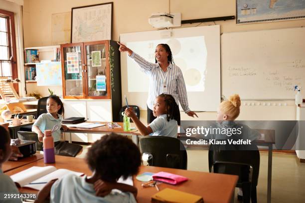 young teacher pointing while teaching in class - teacher pointing finger stock pictures, royalty-free photos & images