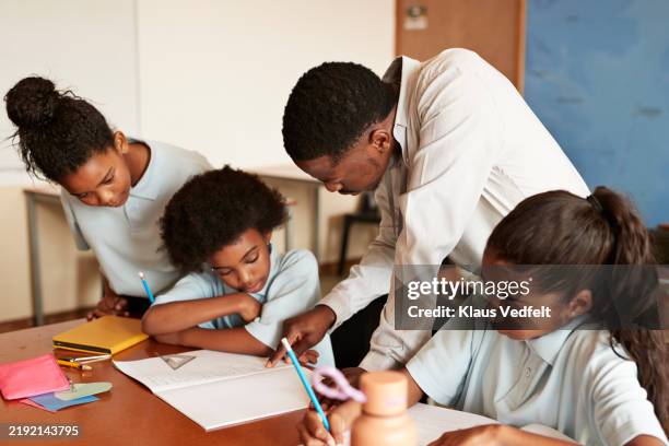teacher leaning on desk and explaining students - math tutor stock pictures, royalty-free photos & images