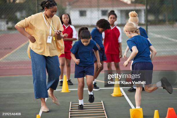 coach with focused girl doing ladder drill - schulsport stock-fotos und bilder