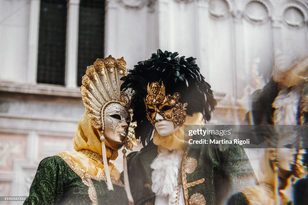 Paarporträt in aufeinander abgestimmten grünen und goldenen Kostümen und Masken während des Karnevals von Venedig, kaleidoskopischer Effekt