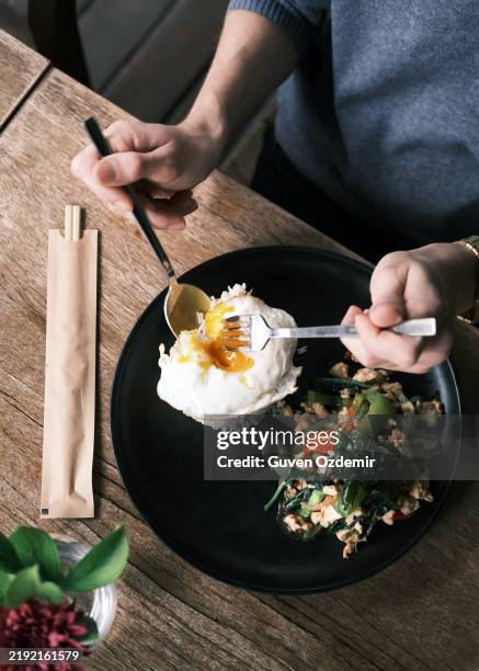 thai stir-fried chicken with hot basil served with jasmine rice and a perfectly fried egg, presented on a black plate in a rustic setting - estilismo culinário imagens e fotografias de stock