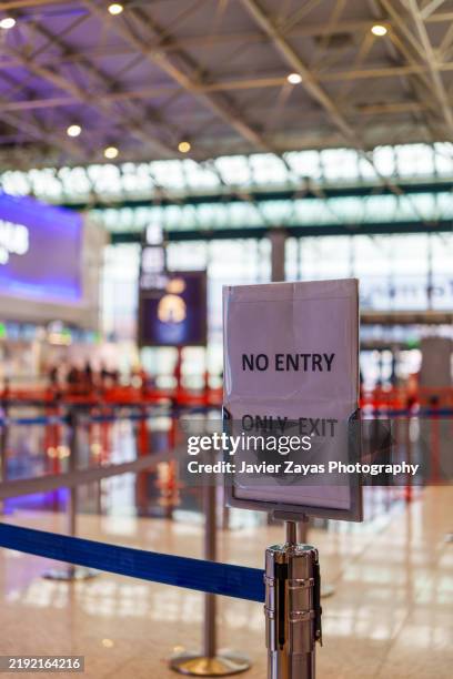 airport terminal exit sign indicating passenger flow direction, directing travelers through organized queue management system - active denial system stock pictures, royalty-free photos & images