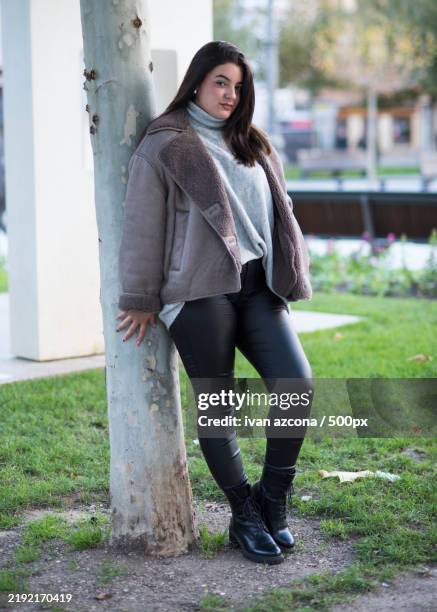 portrait of young woman standing by tree trunk - azcona stock pictures, royalty-free photos & images