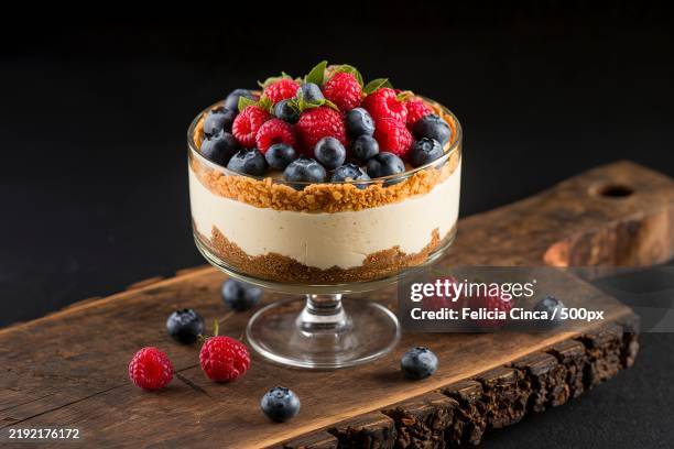 a cheesecake in a glass on a rustic black background - cheesecake stock pictures, royalty-free photos & images