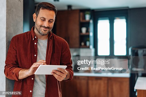 Man using digital tablet in modern kitchen Man using digital tablet in modern kitchen