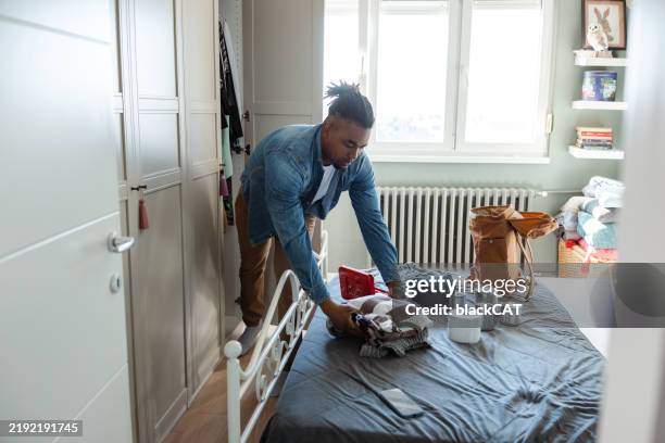 hombre organizando suministros de emergencia en una cama en un dormitorio luminoso y organizado - preparación de alimentos fotografías e imágenes de stock