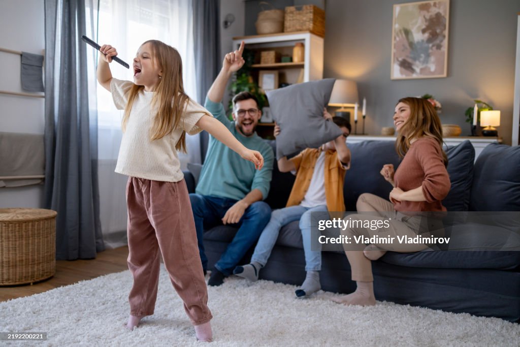 Girl performing karaoke in front of cheering family