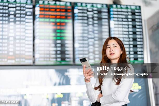 while waiting for her flight at the airport terminal, a young asian woman carrying a luggage uses a smartphone. an asian businesswoman travelling for work. technology and lifestyle. the idea of travel and vacation - virtual office tour stock pictures, royalty-free photos & images
