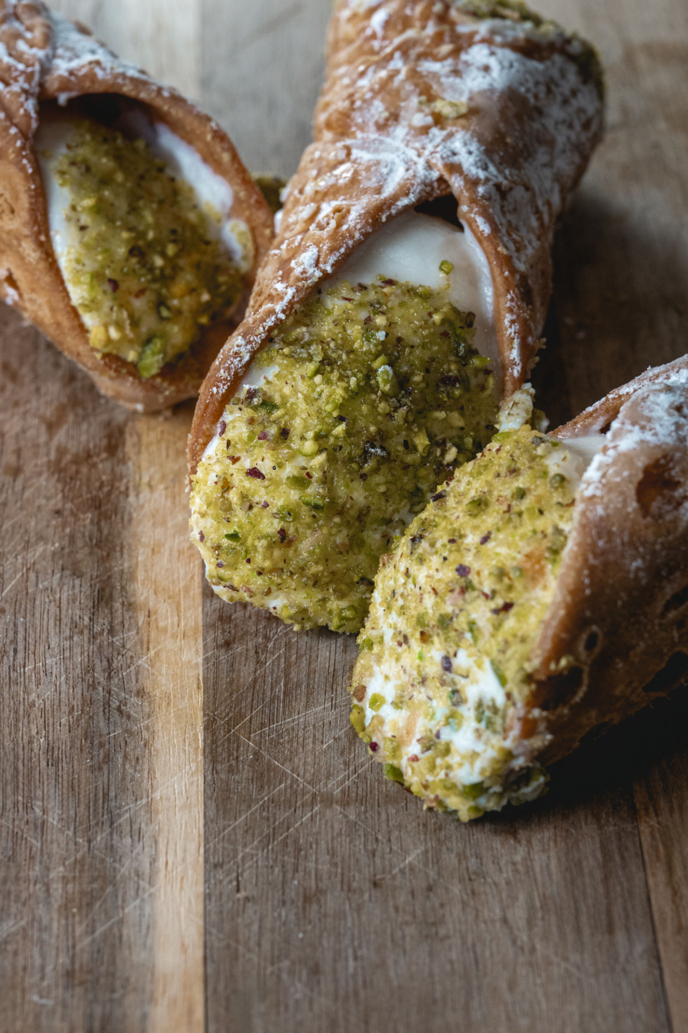 Traditional Sicilian cannoli with pistachio topping on a wooden board Traditional Sicilian cannoli with pistachio topping on a wooden board