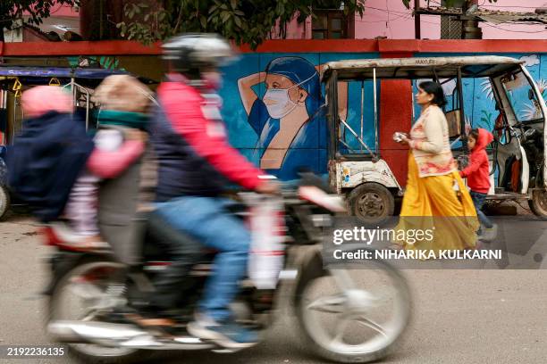 Woman walks past a wall mural promoting awareness on using face masks, in Varanasi on January 7 amid alleged media reports suggesting that the Indian...