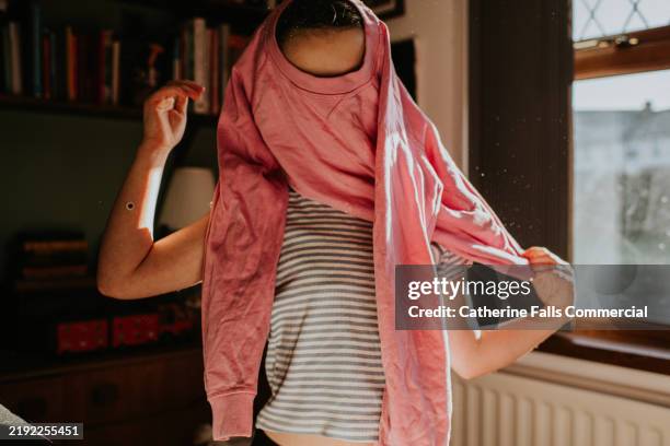 a child pulls on a pink sweater - aankleden stockfoto's en -beelden