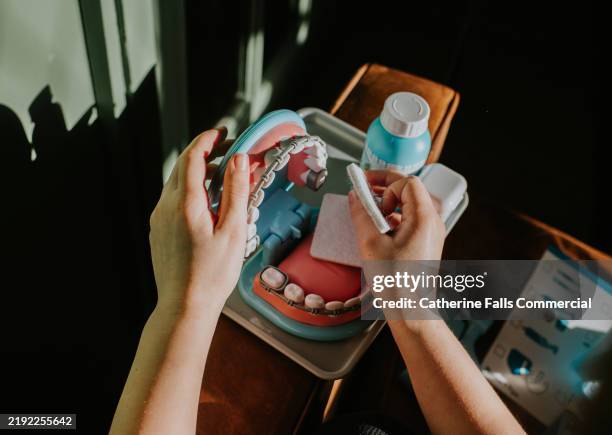 a child pretends to be a dentist, using a simple dentist toy, including a set of teeth, opened to a 90 degree angle - zahnarzthelfer stock-fotos und bilder