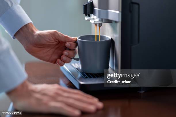 uomo d'affari che prepara una tazza di caffè con la macchina da caffè - macchina per il caffè foto e immagini stock