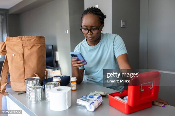 woman checking medicine bottles in a kitchen setup for emergency preparation - first aid kit stock pictures, royalty-free photos & images