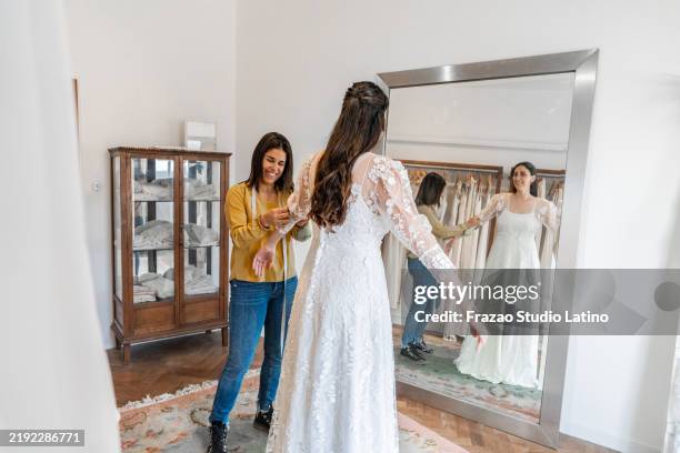 sarta che regola l'abito della sposa in un negozio di abiti da sposa - wedding planning foto e immagini stock