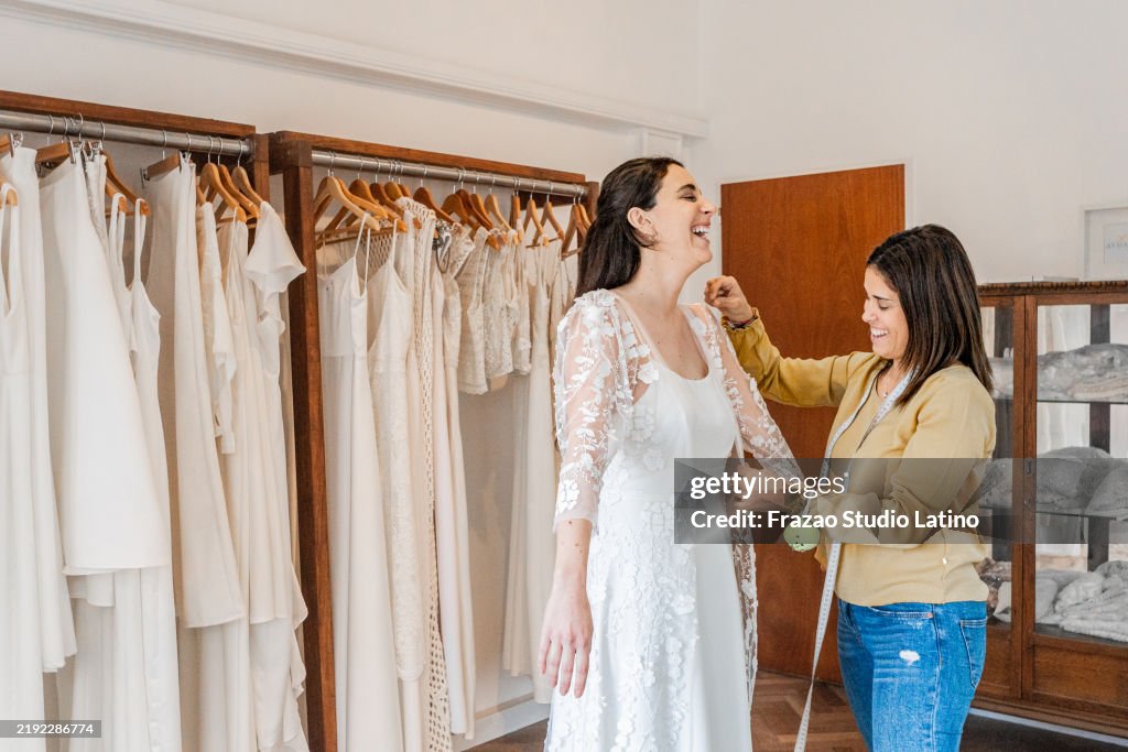 Sarta che regola l'abito della sposa in un negozio di abiti da sposa