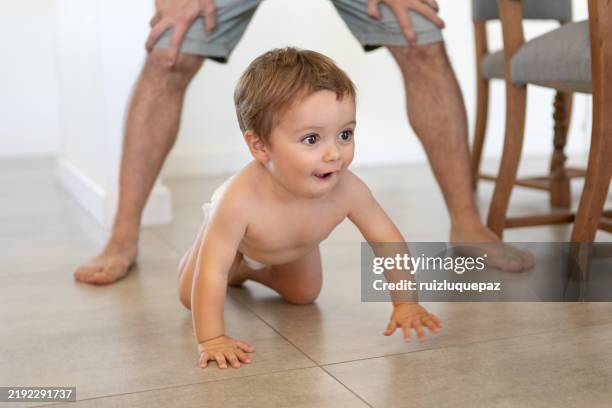 cute naughty boy in diapers crawling at home - crawling stock pictures, royalty-free photos & images