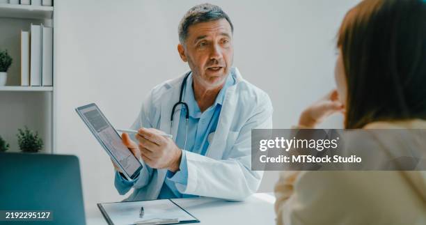 leitender arzt im laborkittel mit digitalem tablet bespricht medizinische testergebnisse mit einem patienten in der klinischen praxis. medizinische versorgung. - medizinische testergebnisse stock-fotos und bilder