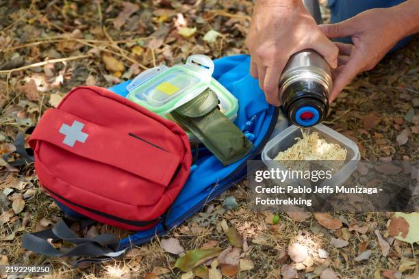 prepper pouring hot water on instant noodles in the woods - survivalist stock pictures, royalty-free photos & images