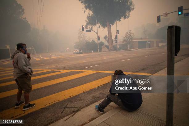 People stop to take a breath as they evacuate along Sunset Boulevard while the Palisades Fire burns amid a powerful windstorm on January 7, 2025 in...