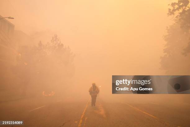 Firefighter walks through the smoke from the Palisades Fire on Sunset Boulevard amid a powerful windstorm on January 7, 2025 in the Pacific Palisades...