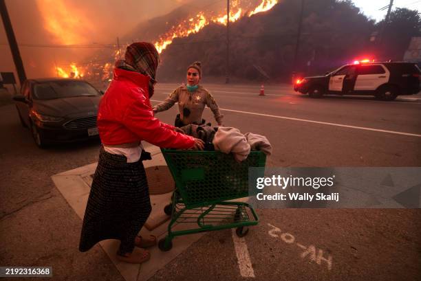Pacific Palisades, CA A police officer escorts a homeless woman to evacuate away from Pacific Coast Highway and Topanga Canyon Blvd as the Palisades...