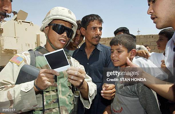 Sgt. First Class John LaCuesta of Reno, NV, from the US Army 1st Brigade, 9th Field Artillery, shows a Polaroid photograph he took of a group of...