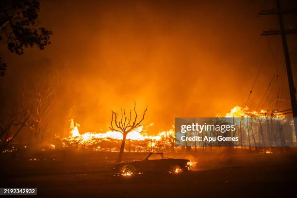 Flames from the Palisades Fire burns a car and homes during a powerful windstorm on January 8, 2025 in the Pacific Palisades neighborhood of Los...