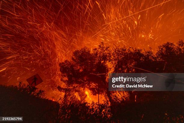 Strong winds blow embers from homes burning in the Eaton Fire on January 7, 2025 in Pasadena, California. A powerful Santa Ana wind event has...