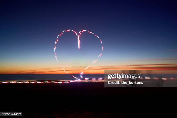 white and red light trails in heart shape at sea after sunset, light painting - dotted line stock pictures, royalty-free photos & images