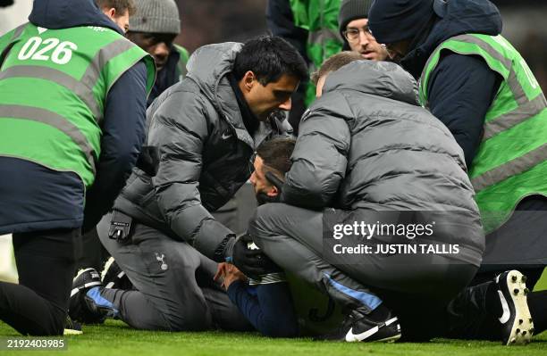 Medical staff treat an injured Tottenham Hotspur's Uruguayan midfielder Rodrigo Bentancur during the English League Cup semi-final first leg football...