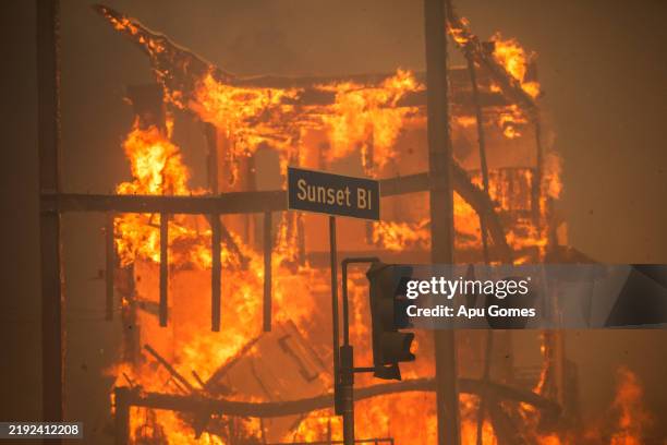 Flames from the Palisades Fire burn a building on Sunset Boulevard amid a powerful windstorm on January 8, 2025 in the Pacific Palisades neighborhood...