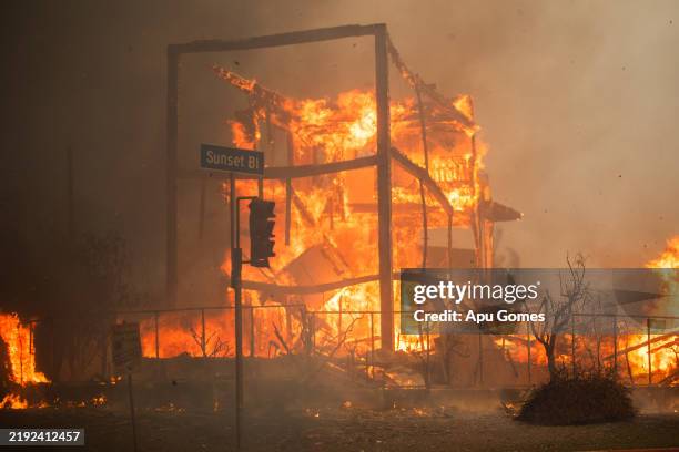 Flames from the Palisades Fire burn a building on Sunset Boulevard amid a powerful windstorm on January 8, 2025 in the Pacific Palisades neighborhood...