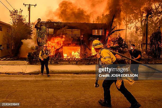 Firefighters work the scene as an apartment building burns during the Eaton fire in the Altadena area of Los Angeles county, California on January 8,...